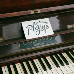 Upright piano with card that says "go ahead play me"